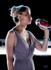 a woman is drinking from a bottle that says vodka