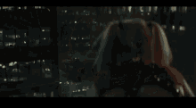 harley quinn from suicide squad is standing on a rooftop at night .