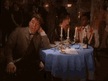 a man sitting at a table with candles and a bottle of champagne