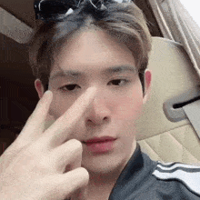 a young man is sitting in a car making a peace sign with his fingers .