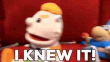 a puppet says i knew it in front of a red wall