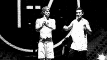 a man without a shirt is standing next to another man on a stage in a black and white photo .