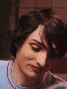 a close up of a young man 's face wearing a blue shirt