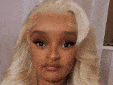 a woman with blonde hair is wearing a blue sweater and holding her hair .