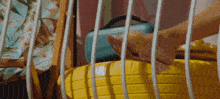 a woman 's foot rests on a yellow suitcase behind a fence