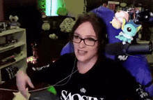 a woman wearing glasses is sitting in a chair with a stuffed animal on her back .