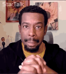 a man with a beard is sitting in front of a wall with a picture of sunflowers and the words star talk written on it
