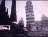 a group of people are walking in front of a very tall tower in a city .