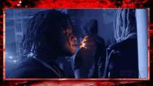 a man with dreadlocks is smoking a cigarette in a dark room with a youtube logo in the background