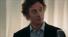 a man with curly hair and a blue shirt is looking at something