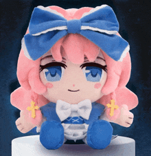 a stuffed doll with pink hair and a blue bow is sitting on a white surface