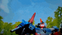 a red and blue robot with a gun on its arm
