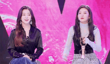 two young women are sitting next to each other on a stage .
