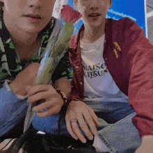 a man wearing a maison kitsune shirt sits next to another man