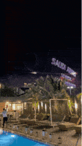 a saudi arabia sign is lit up at night over a swimming pool