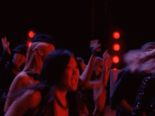 a group of women are dancing in a dark room with red lights behind them