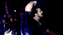 a man with a bracelet on his wrist holds his hand to his forehead