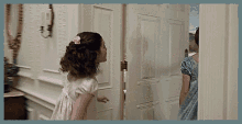 a little girl in a white dress stands in a hallway