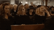 a large group of people are sitting in a church watching a funeral .