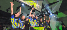 a group of men are holding a trophy in their hands while standing in front of a large screen .