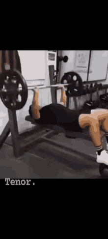 a man is doing a bench press in a gym with a barbell .