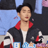a man wearing a balenciaga jacket is standing in front of a sign that says hello asian