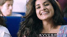 a woman is smiling with kvvcsr in the corner