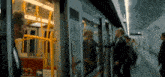 a group of people are boarding a train with a green sign that says emergency exit