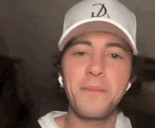 a man wearing a white baseball cap and ear buds is making a funny face .