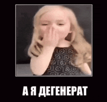 a little girl is covering her nose with her hand and making a funny face .
