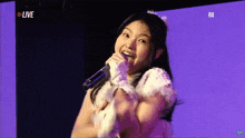 a girl singing into a microphone in front of a live screen