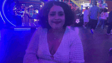a woman in a white sweater is smiling in an arcade with the name shagarita on the bottom right