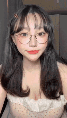 a young woman wearing glasses and a white top