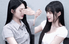 a woman covering her eyes with her hand while another woman touches her face