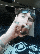 a man wearing sunglasses and a ring is smoking a pipe