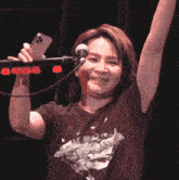 a woman singing into a microphone while holding a cellphone