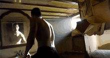 a shirtless man stands in front of a mirror looking at himself