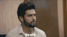 a man with a beard is sitting in a chair and saying `` it 's ok '' .