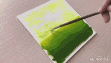 a brush is being used to apply green paint to a piece of paper