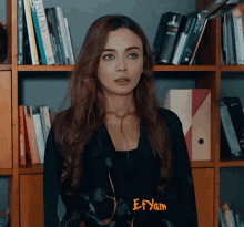 a woman standing in front of a bookshelf with the name efyam written on the bottom
