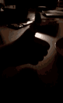 a person 's hand is visible on a wooden table in the dark