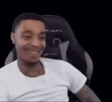 a man in a white shirt is sitting in a chair and smiling .