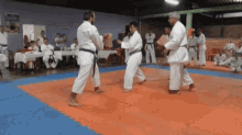a group of people in white karate uniforms are practicing on a mat