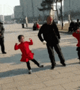 a little girl in a red dress is dancing with her father