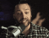 a man speaking into a shure microphone in a plaid shirt
