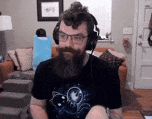 a man with a beard and glasses is wearing headphones and a cat shirt .
