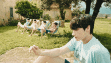 a boy in a blue shirt sits in front of a group of men sitting in chairs