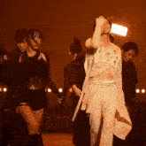 a woman in a white crop top and white pants is holding a microphone