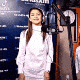 a woman in a white dress is standing in front of a microphone in a studio .