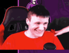 a man in a red shirt is sitting in a chair and smiling